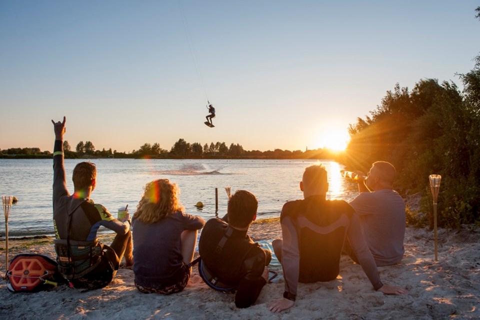 Kitesurfers zitten op strand, zonsondergang